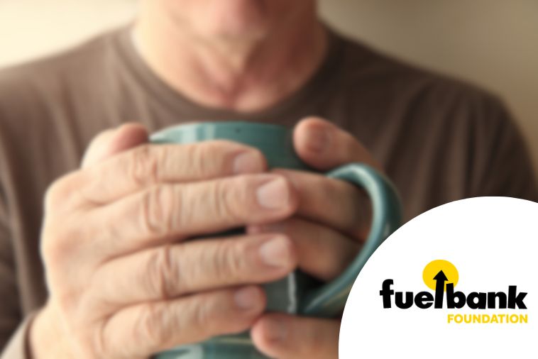 mens hands wrapped around a mug. with fuel bank foundation logo in the bottom corner.